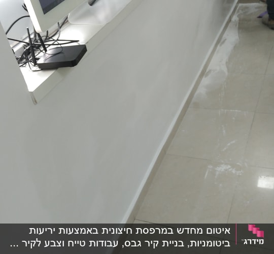 אדם מורח חומר איטום על הרצפה ליד הקיר